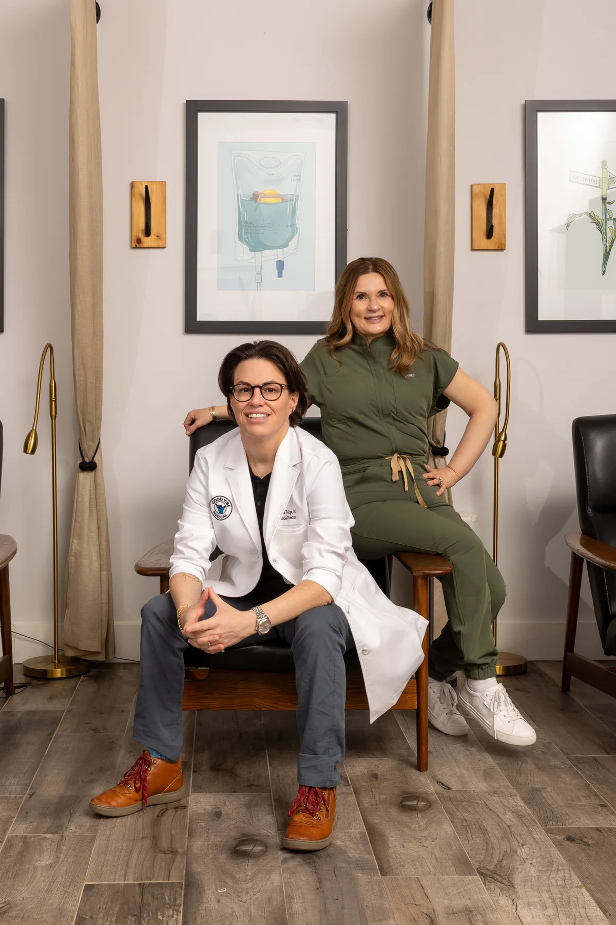 Two clinicians in the consultation lounge — the medical director in a white coat seated beside a colleague in scrubs