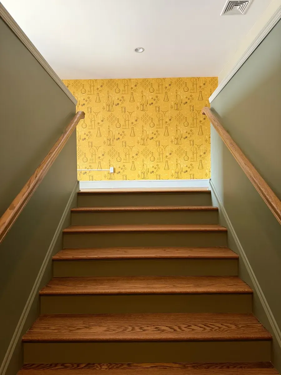 Stairway rising toward a chemistry-print accent wall inside the Good Gene practice
