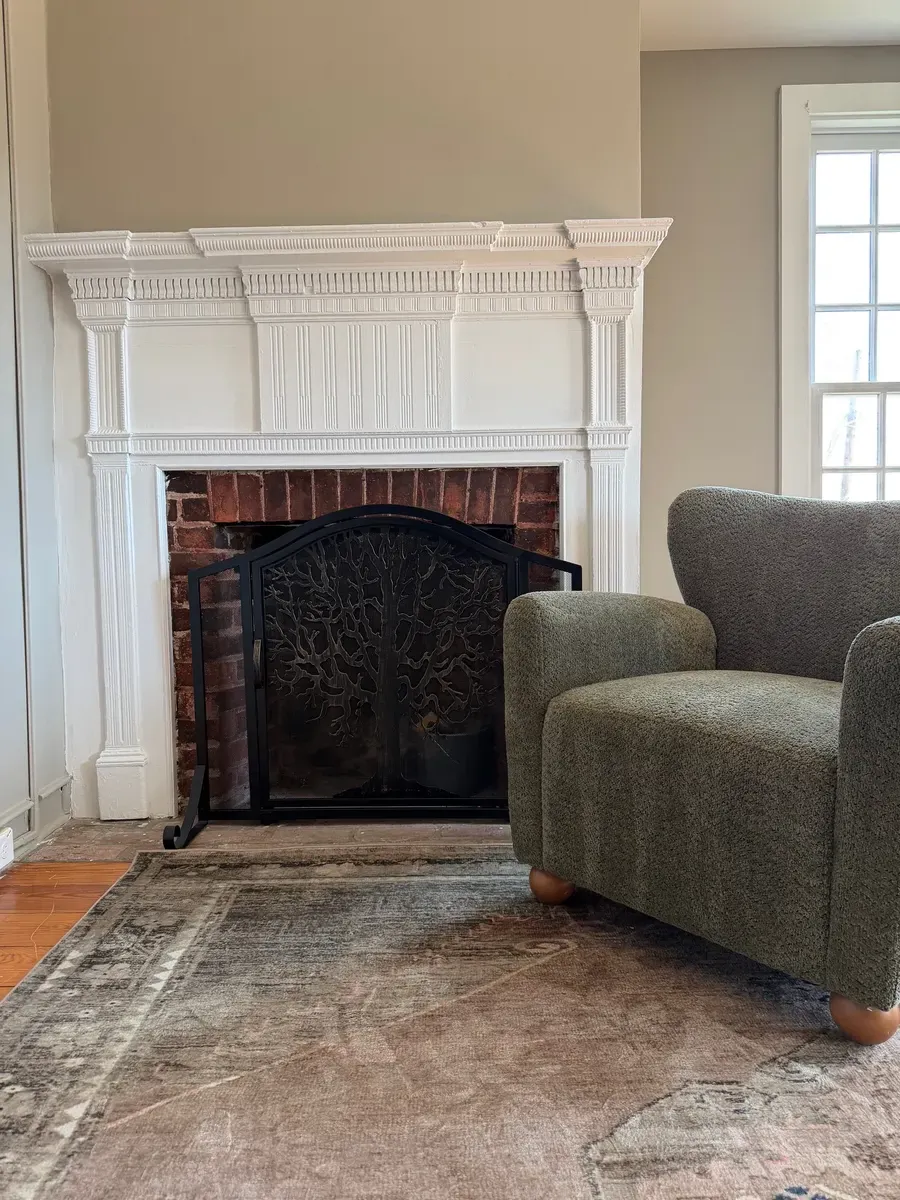 Sitting area with an upholstered armchair beside the original fireplace at the Good Gene practice